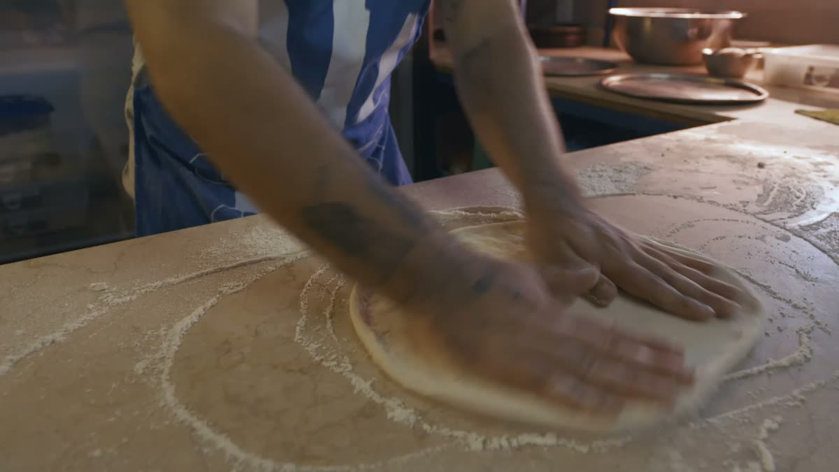 Le pizzaïolo façonne la pâte à la main